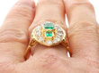 1930's emerald ring with diamonds on finger
