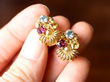 holding gemstone earrings in gold
