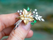 holding a Vintage Emerald and Pearl Flower Brooch