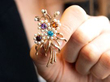holding a multi gemstone brooch in gold