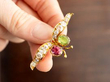 holding a peridot and kunzite brooch