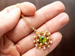 holding a gold peridot pendant with pearls