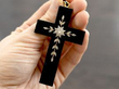 holding a black onyx cross pendant