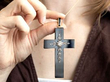 holding a black onyx cross pendant with diamonds