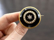 holding a circular black onyx brooch